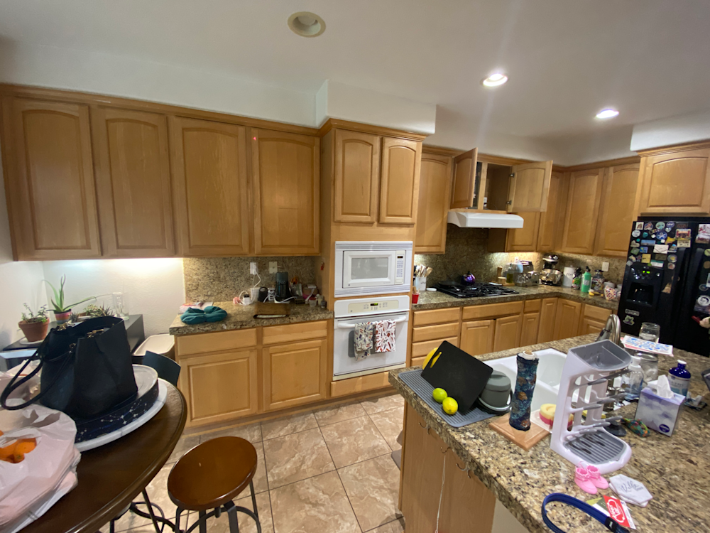 Cluttered kitchen with oak cabinets, granite countertops, and modern appliances in Sacramento