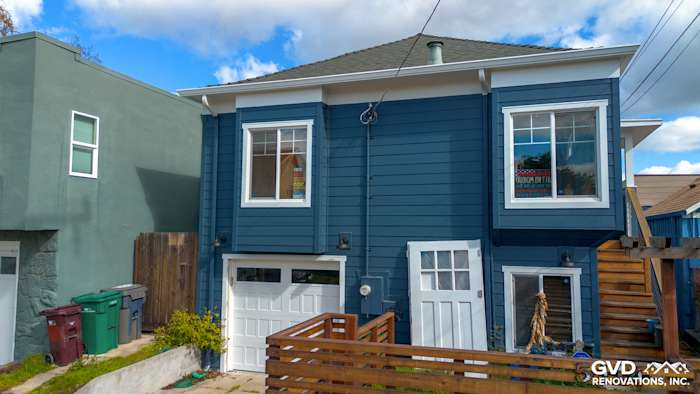 Oakland home exterior featuring new James Hardie Evening Blue siding and Arctic White trim with modern garage doors