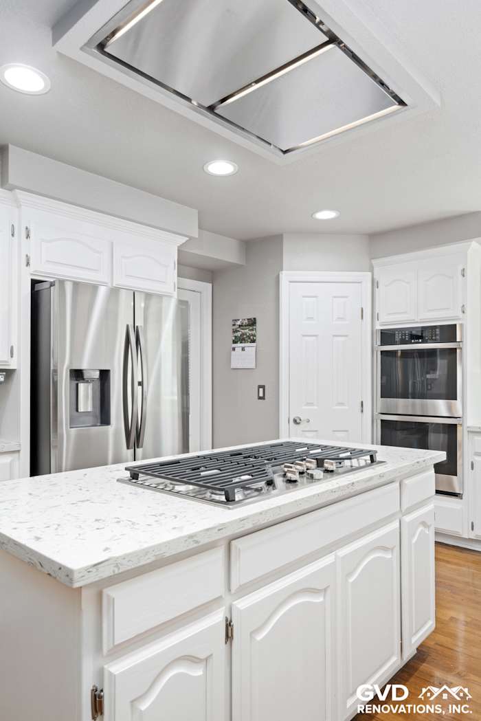 Bright, modern kitchen with white cabinetry, quartz countertops, built-in appliances, and a center gas cooktop