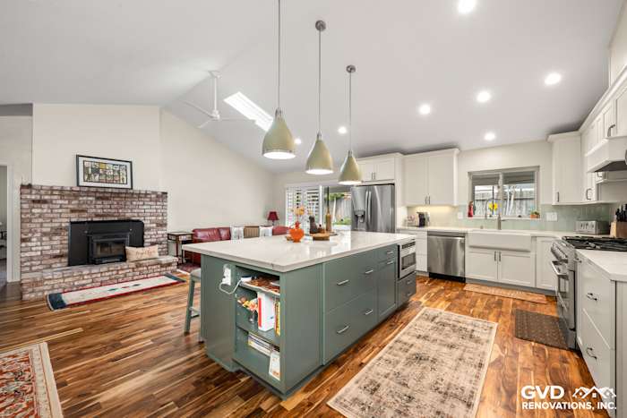 Spacious kitchen remodel featuring an island with custom green cabinets, white countertops, and modern fixtures