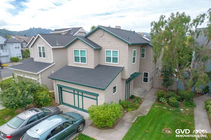 Two-story home exterior in San Rafael featuring new Anlin Catalina windows and repaired siding, surrounded by greenery