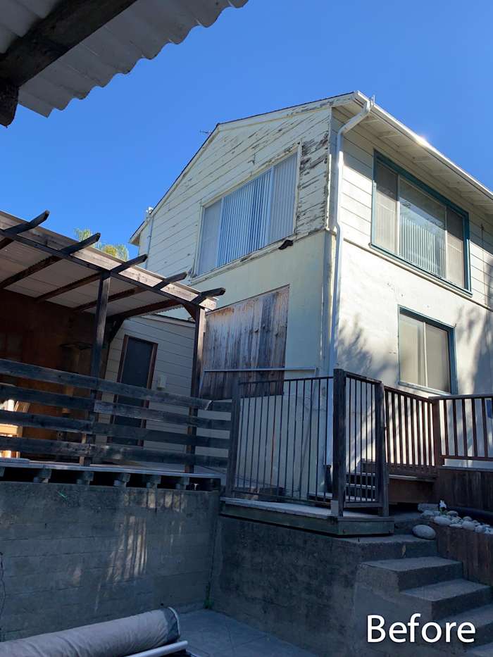 Weathered home exterior with peeling paint, wooden deck, and old vinyl windows before renovation in Oakland