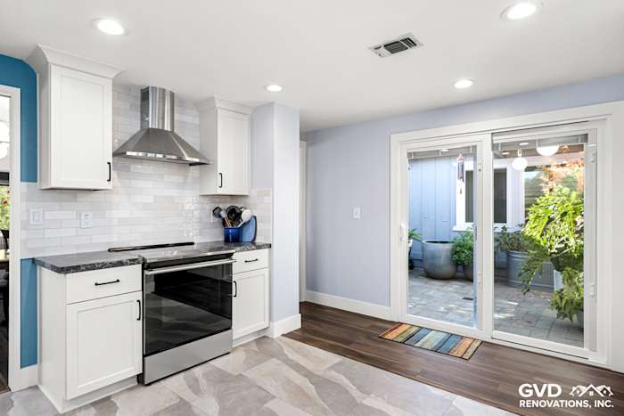 Modern kitchen with white cabinetry, quartz countertops, stainless steel appliances, and sliding glass doors to a patio