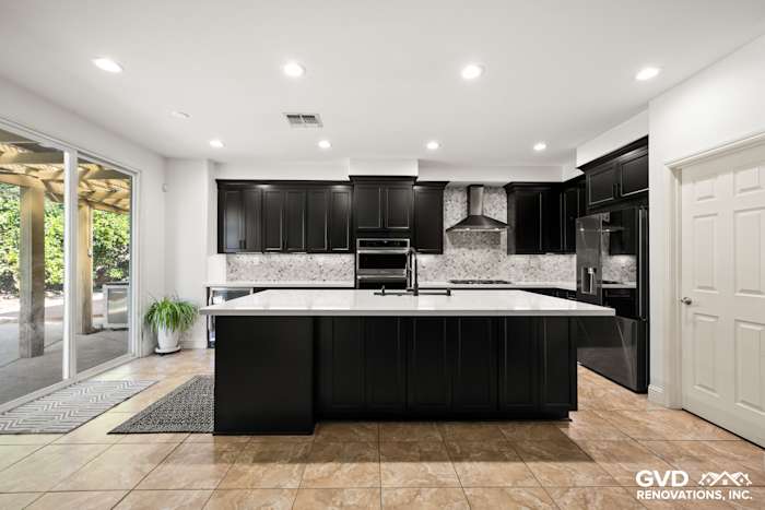 Modern kitchen remodel in Roseville with black Waypoint cabinets, white MSI countertops, and elegant backsplash
