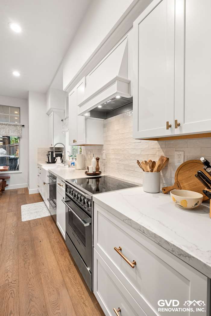Modern kitchen remodel featuring white Waypoint cabinets, Vadara Bronzo countertops, and a stylish wood floor in Folsom, CA