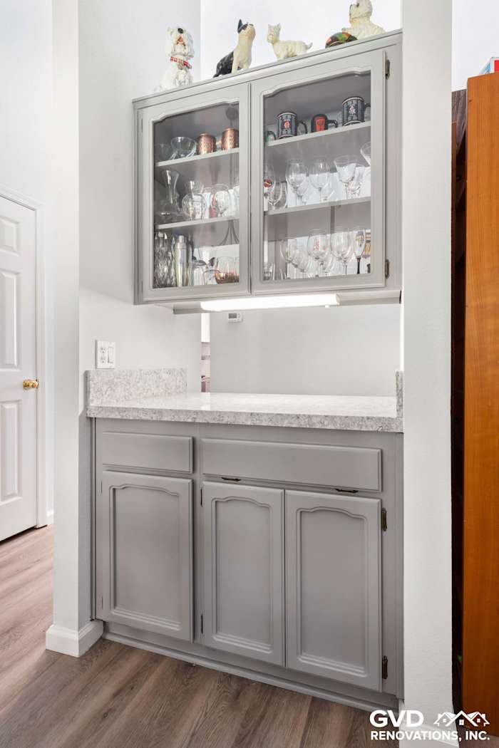 Gray cabinetry with glass display, quartz countertop, and elegant decor in a modern kitchen remodel in Carmichael