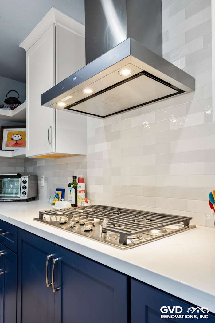 Contemporary kitchen with navy blue cabinetry, stainless steel gas range, and stylish backsplash in Fair Oaks, CA