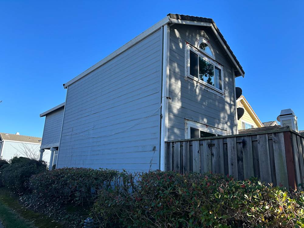 Gray exterior siding with overgrown shrubs in Sacramento, showcasing a residential remodeling project