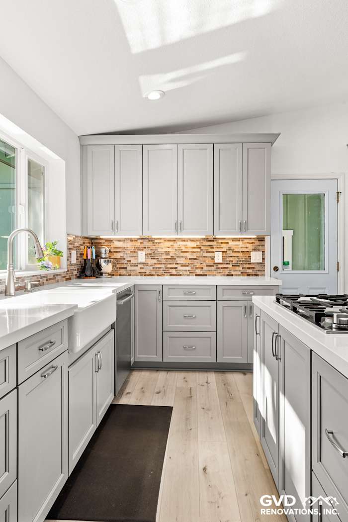 Modern kitchen remodel in Greenwood, CA featuring gray cabinetry, quartz countertops, and textured backsplash