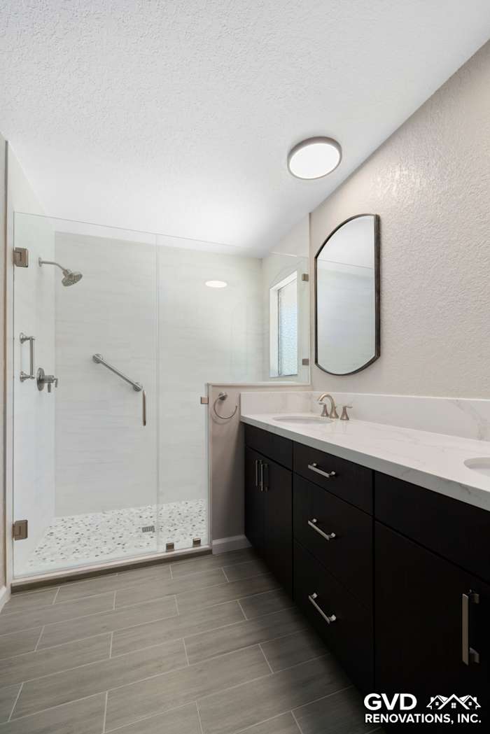 Modern master bathroom with glass shower, dark cabinetry, quartz countertop, and sleek mirror in Rocklin, CA