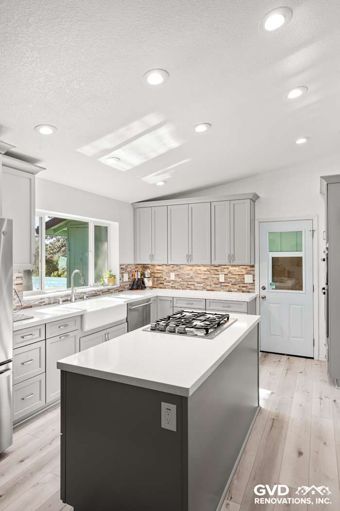 Modern kitchen with gray cabinets, white quartz countertops, and stacked stone backsplash in Greenwood, CA