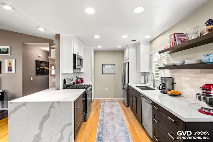 Modern kitchen remodel featuring two-tone cabinetry, quartz countertops, stainless steel appliances, and warm hardwood