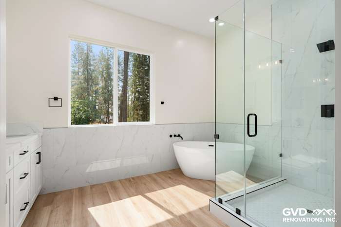 Modern bathroom with freestanding tub, glass shower, white cabinetry, and wood-look floor in Paradise, CA