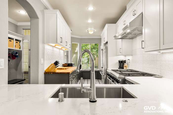 Spacious modern kitchen with white cabinetry, quartz countertops, and stainless steel appliances in Folsom remodel