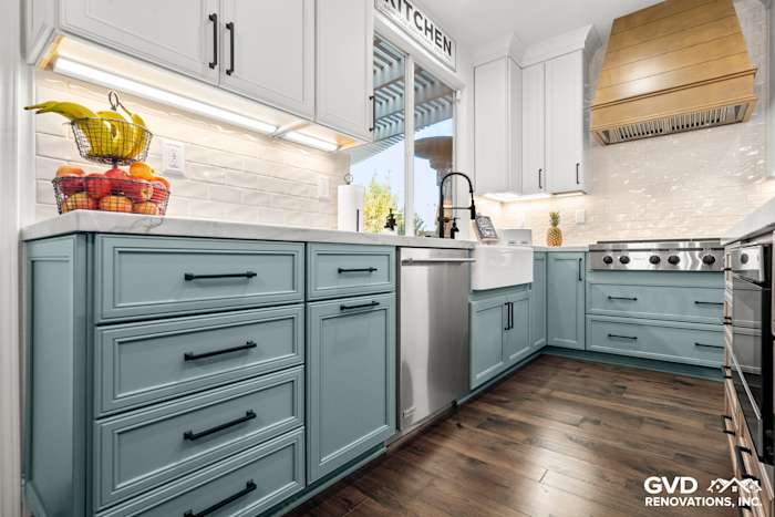 Modern kitchen with blue base cabinets, white quartzite countertops, stainless steel appliances, and elegant backsplash