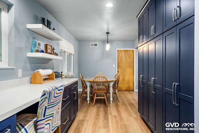 Bright kitchen remodel featuring navy blue cabinetry, a sleek white counter, and a cozy dining area with wood chairs