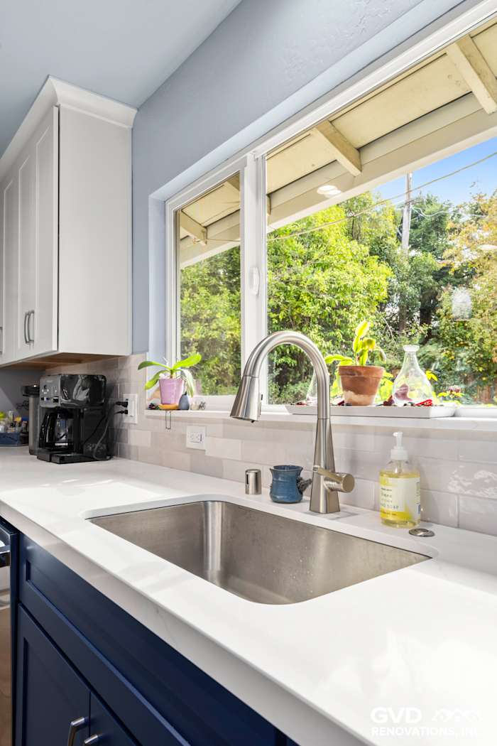 Bright kitchen sink area with a modern faucet, quartz countertop, and window view showcasing greenery