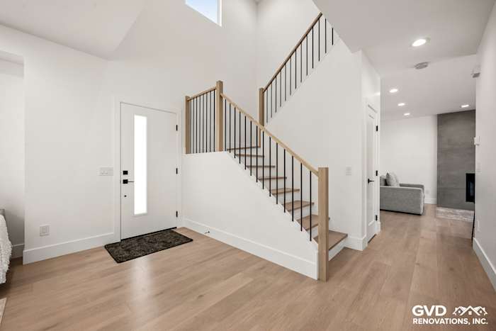 Bright entryway featuring a modern staircase with wooden handrails and new flooring in Antelope, CA home remodel