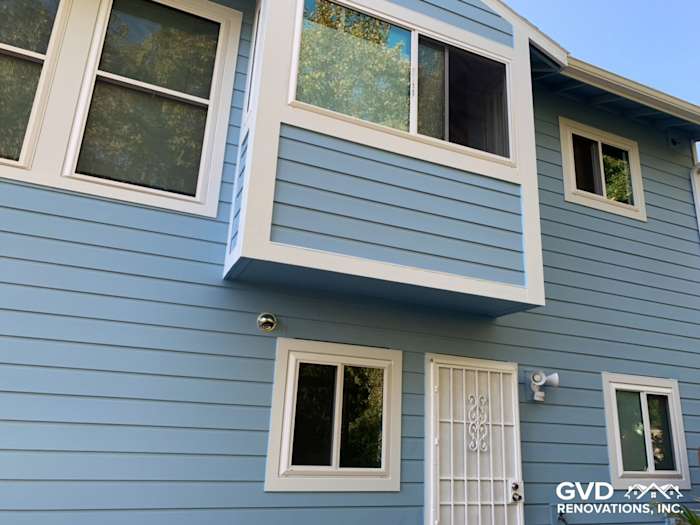 Newly renovated home exterior featuring James Hardie Smooth Lap Siding in light blue and vinyl windows in Oakland