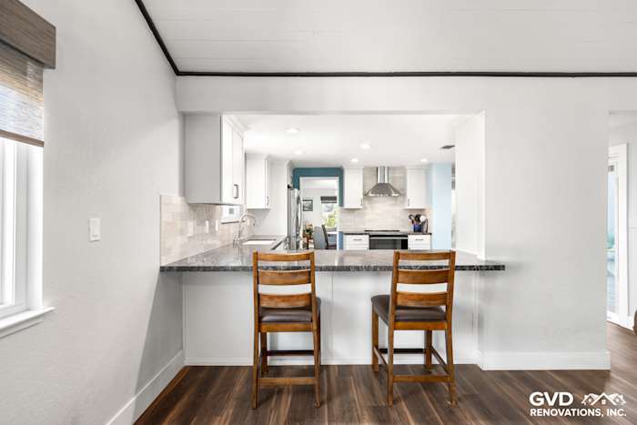 Modern Fair Oaks kitchen remodel featuring granite countertop, white cabinets, and bar seating with wooden chairs