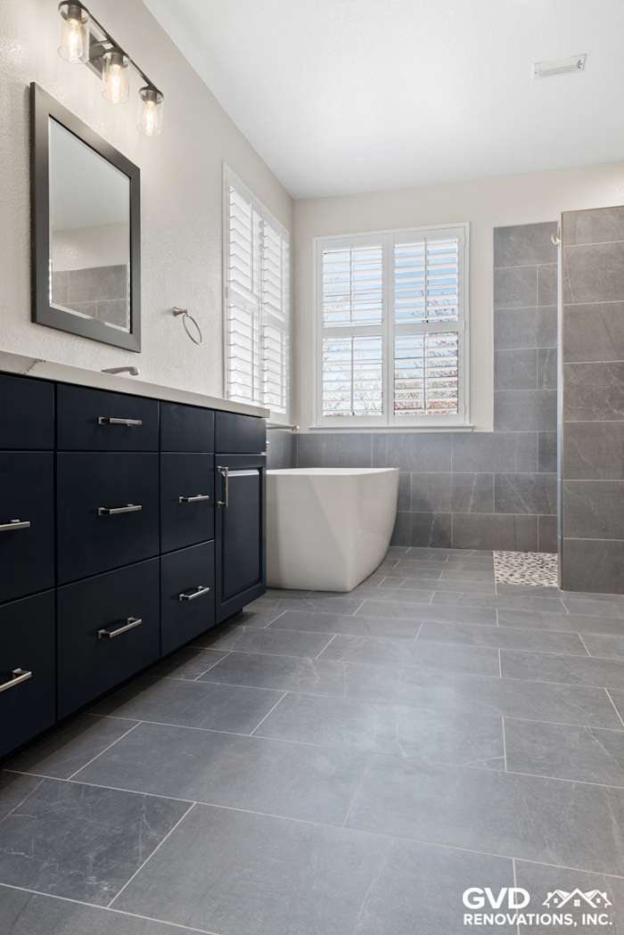 Modern master bathroom featuring dark cabinetry, freestanding tub, and gray tile flooring in El Dorado Hills