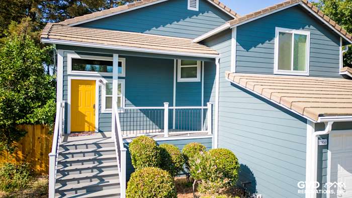 Updated exterior of home with new blue siding, Anlin windows, and yellow front door in Dixon, CA