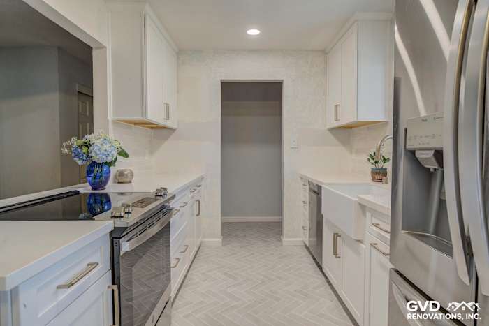 Modern kitchen with white cabinets, quartz countertops, herringbone tile, and stainless steel appliances