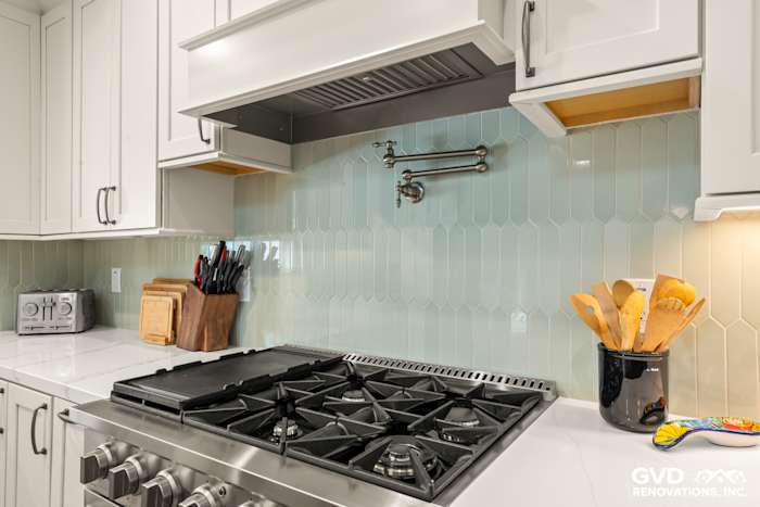 Modern kitchen with a white backsplash, gas stove, and custom cabinetry featuring stylish kitchen utensils