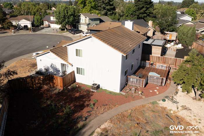 Modern home exterior featuring newly installed white siding, brown roof, and a spacious backyard deck in Petaluma