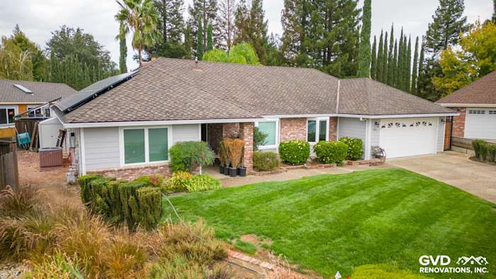 Home exterior in Roseville featuring James Hardie Cedarmill siding, HardieTrim, and Milgard windows. Lush landscape included
