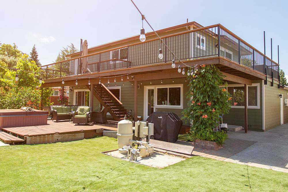 Fresh green siding, updated outdoor seating, modern deck railings, and vibrant landscaping