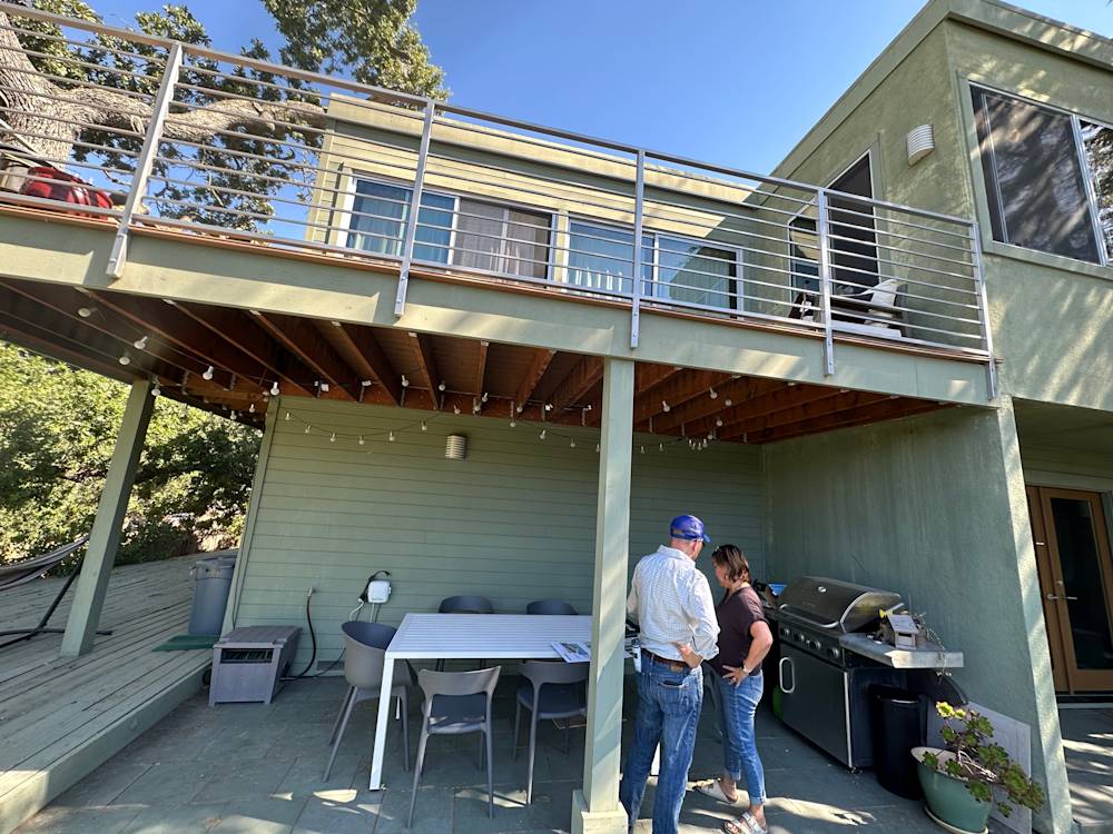 Under-deck patio area featuring green walls, wooden beams, and outdoor dining setup in Sacramento
