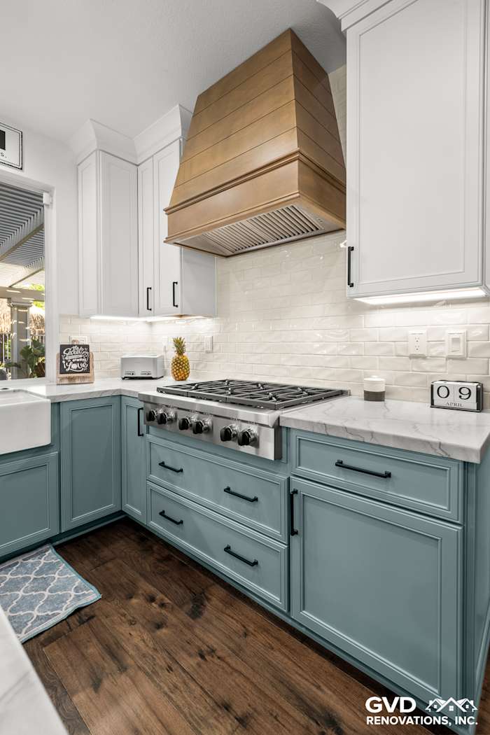 Kitchen remodel in Roseville featuring blue base cabinets, white quartzite countertop, and a stylish range hood