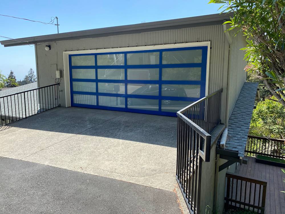 Concrete driveway leading to a modern blue glass garage door in Sacramento