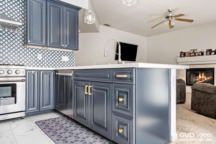 Modern kitchen with navy blue cabinets, white quartz countertop, stainless steel appliances, and patterned backsplash