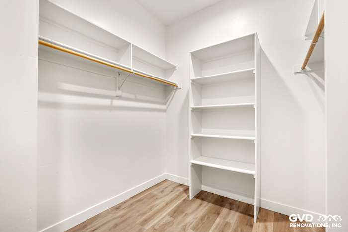 Bright and spacious walk-in closet with white shelving and wooden flooring in a new home construction