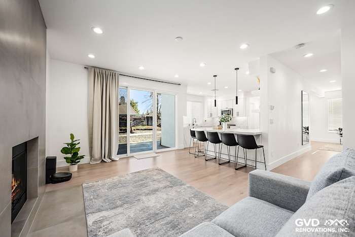 Modern living room with a sleek fireplace, new flooring, and bright sliding doors to the backyard