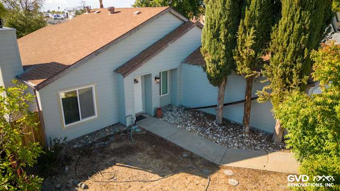 Updated home exterior featuring James Hardie siding in light blue with a brown shingle roof and landscaped entryway