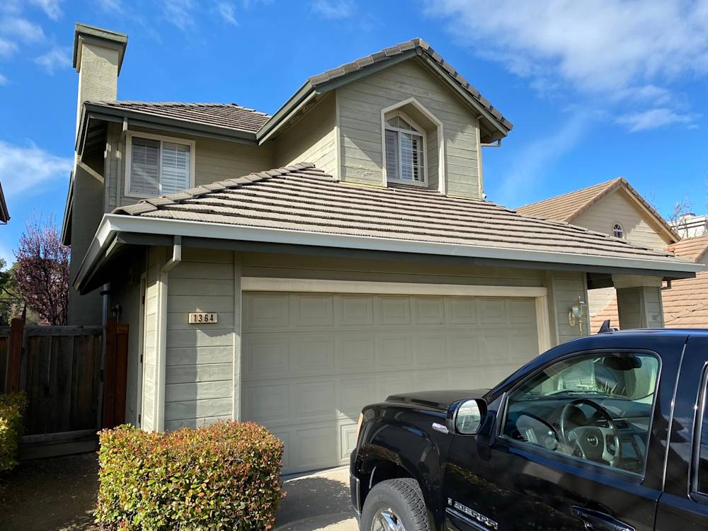 A suburban home in Sacramento with a light green exterior, dark roof, and two-car garage