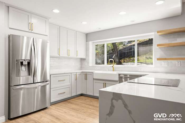Modern kitchen with custom white cabinets, quartz countertops, stainless steel appliances, and large window in El Dorado