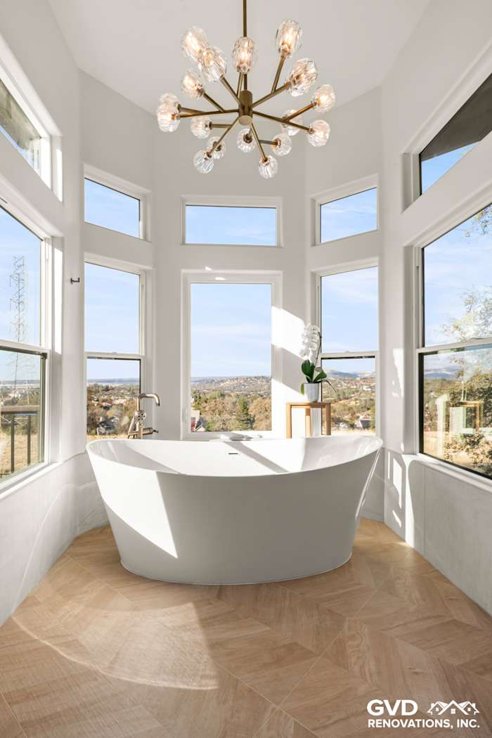 Bright and airy bathroom featuring a freestanding BainUltra air jet tub with scenic views from multiple windows