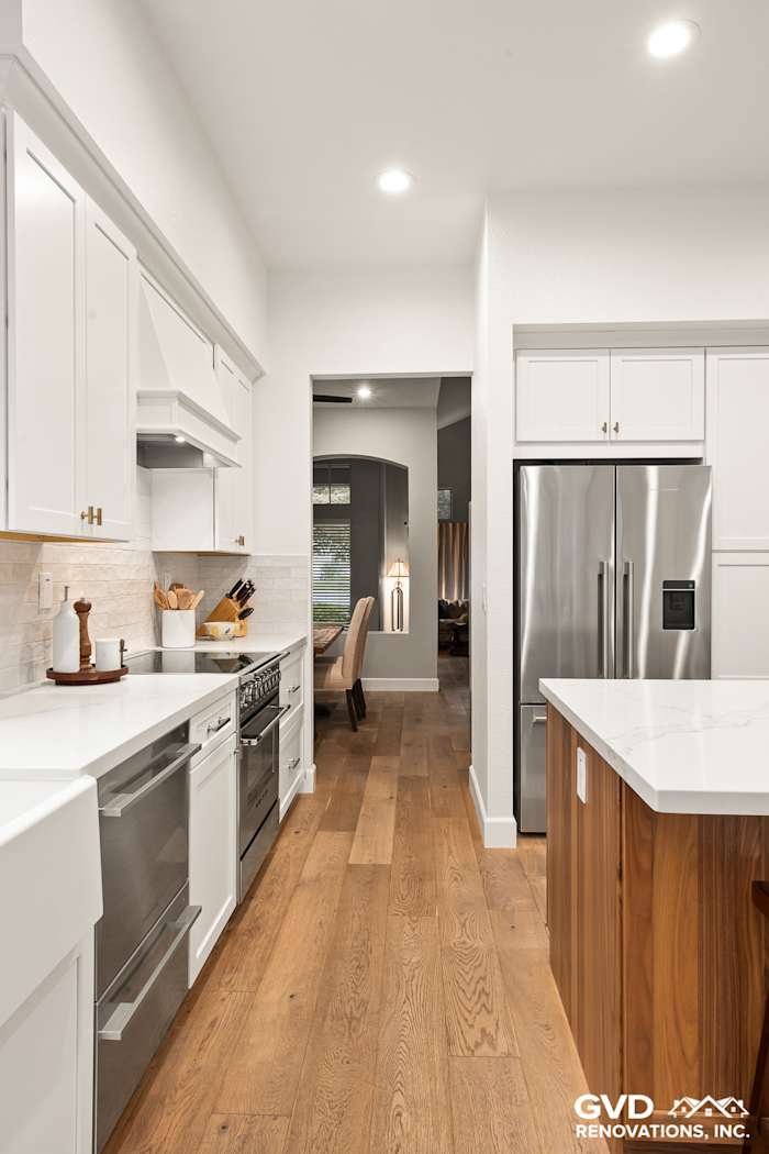 Modern kitchen with Waypoint cabinets, Vadara Bronzo countertops, stainless steel appliances, and hardwood floors