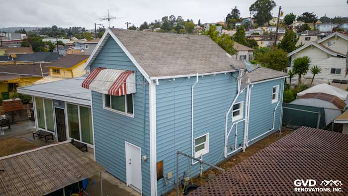Light blue Alside Prodigy vinyl siding on the side of a renovated home in Oakland with a gray roof