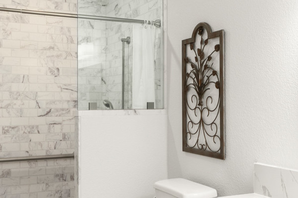 Spacious ADA-compliant bathroom in light tones featuring a walk-in shower and grab bars