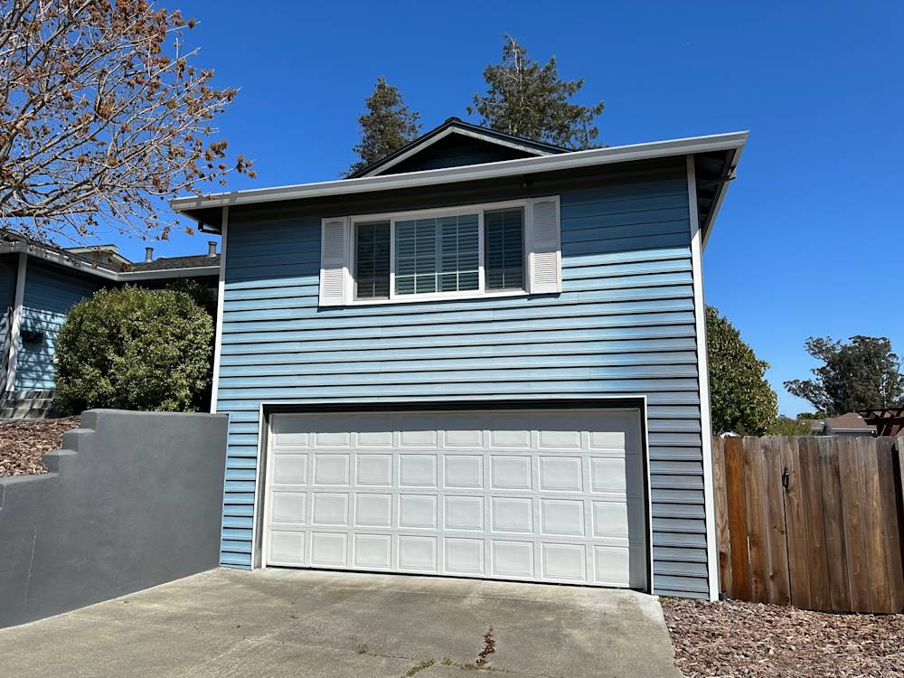 Two-story blue house in Sacramento with a white garage door and landscaped front yard