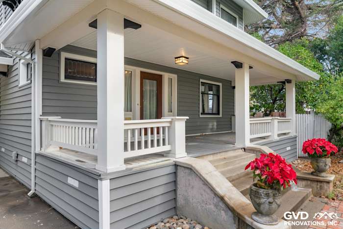 Renovated home exterior in Dixon, featuring new gray vinyl siding, white railings, and seasonal potted plants