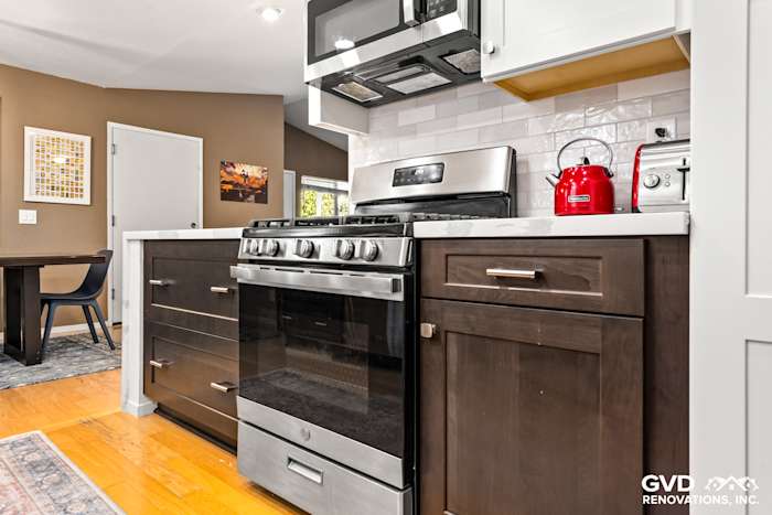 Modern kitchen with dark cabinetry, stainless steel gas range, and white subway tile backsplash in Davis remodel