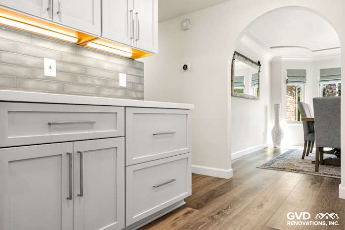 Modern kitchen with white cabinets, gray subway tile backsplash, and wood flooring in Rocklin remodel