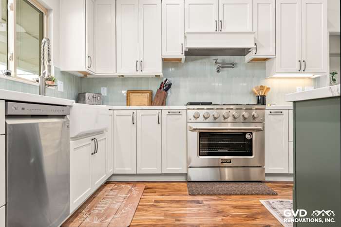 Modern kitchen remodel featuring custom white cabinets, stainless steel appliances, and a light green backsplash