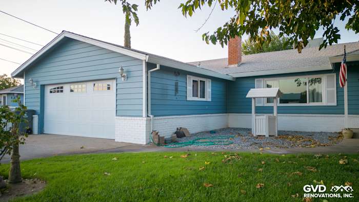 Home exterior featuring new Alside Prodigy vinyl siding in blue, complemented by a white brick foundation and garage